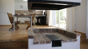 Une cuisine équipée d’un barbecue intégré, un coin repas avec des chaises et une fenêtre laissant entrer la lumière naturelle.