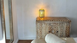 A room with a stone wall, a wooden side table with a patterned cushion, and a mirror. - Cosy Quiet Hideaway with Private Terrace, perfect location old town Tarifa (Tarifa)