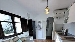 A compact living space with a sofa, a kitchen area, and a view through a window. - Cosy Quiet Hideaway with Private Terrace, perfect location old town Tarifa (Tarifa)