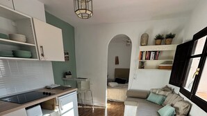 A modern kitchen with white cabinets, a wooden countertop, and a round woven rug. - Cosy Quiet Hideaway with Private Terrace, perfect location old town Tarifa (Tarifa)