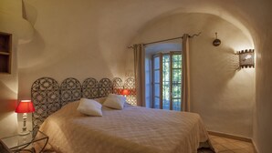 A bedroom with a bed, a nightstand, a lamp, and a window with curtains. - House with character (Feliceto)