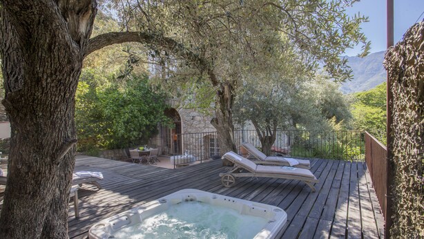 A wooden deck with a hot tub, lounge chairs, and a stone building in the background. - House with character (Feliceto)
