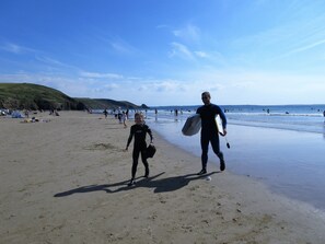 A beach with people walking and surfing.