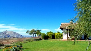 A house with a red-tiled roof, surrounded by a well-maintained lawn and various plants.
