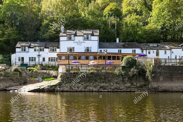 Experience the charm of Ye Olde Sturie Inn, situated by a river with a classic facade and a balcony offering a scenic view.