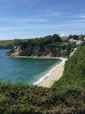 Un paisaje costero con una playa arenosa, acantilados rocosos y vegetación exuberante.
