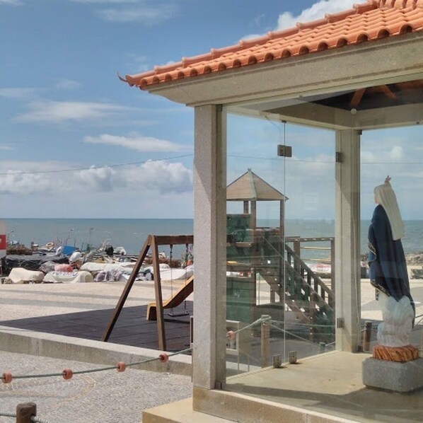 A beachside pavilion with a glass enclosure, a wooden staircase, and a lifeguard tower.