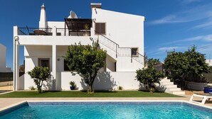 Un edificio moderno e bianco con piscina, una scala e piante in vaso.