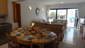 Un soggiorno moderno con zona pranzo, che include un tavolo rotondo apparecchiato per la colazione, un divano e una televisione.