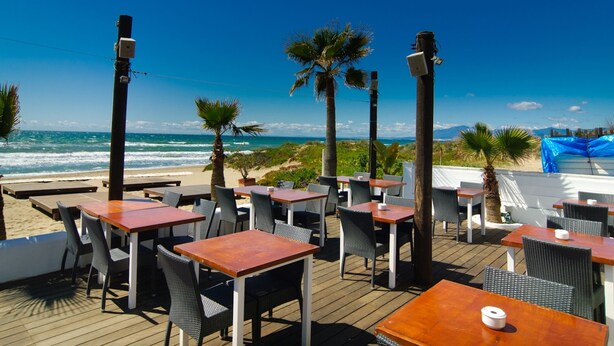 An outdoor seating area with tables and chairs, overlooking the beach and ocean. - Beachside Luxury Villa Private Heated Pool & Sea Views in Las Chapas (Marbella)