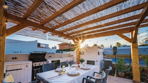 An outdoor patio with a dining table set for four, surrounded by wicker chairs. - Beachside Luxury Villa Private Heated Pool & Sea Views in Las Chapas (Marbella)