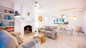 A modern living room with a fireplace, sofa, and dining area. - Beachside Luxury Villa Private Heated Pool & Sea Views in Las Chapas (Marbella)