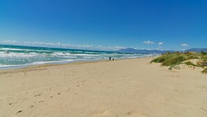 A wide sandy beach with gentle waves, a clear blue sky, and distant mountains. - Beachside Luxury Villa Private Heated Pool & Sea Views in Las Chapas (Marbella)
