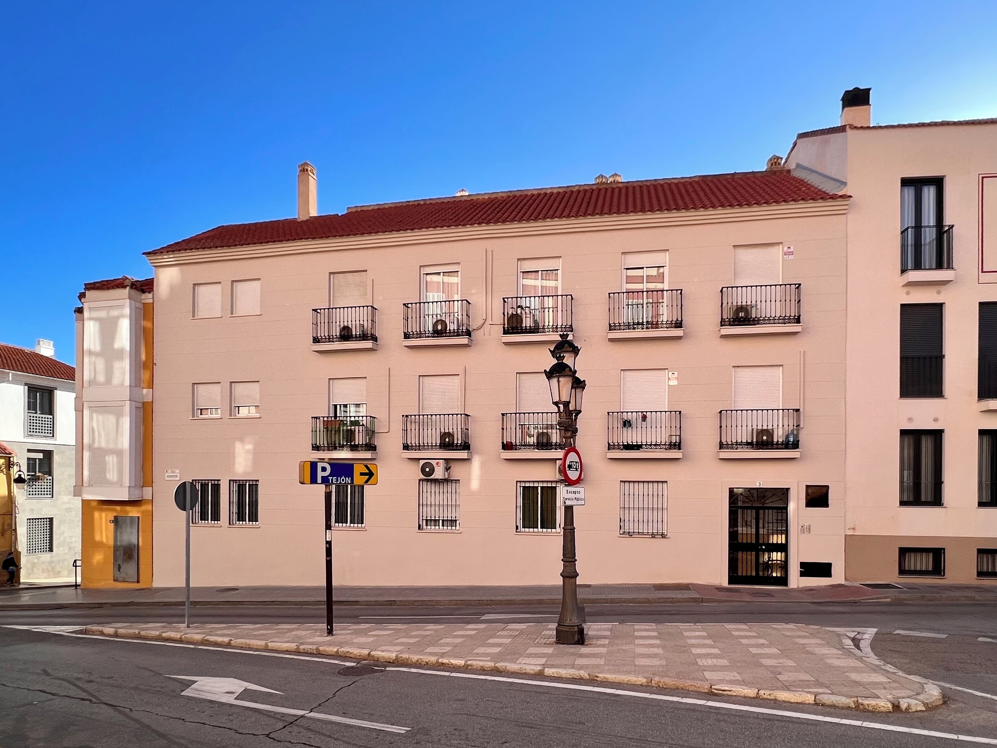 A building with multiple balconies, a parking sign, and a no parking sign.