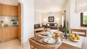 A modern kitchen with wooden cabinets, a microwave, and a dining area with a table set for breakfast. - Algarve, Casa Julio, Albufeira Town, Beside The Strip (Albufeira)