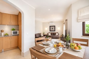 A modern kitchen with wooden cabinets, a microwave, and a dining area with a table set for breakfast.