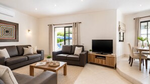 A modern living room with a sofa, a coffee table, a TV, and a dining area with chairs and a table. - Algarve, Casa Julio, Albufeira Town, Beside The Strip (Albufeira)