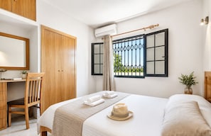 A bedroom with a bed, a desk, a chair, a wardrobe, and a window with a view.