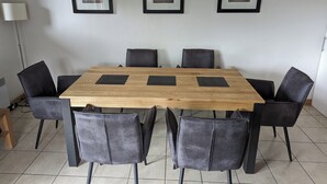 Une salle de conférence avec une table en bois, des chaises noires et des tableaux encadrés accrochés au mur.