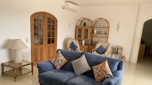 A living room with a blue sofa, a glass coffee table, a wooden side table, and a lamp. - Spacious luxury villa with A/C near beach with private pool (Carvoeiro)