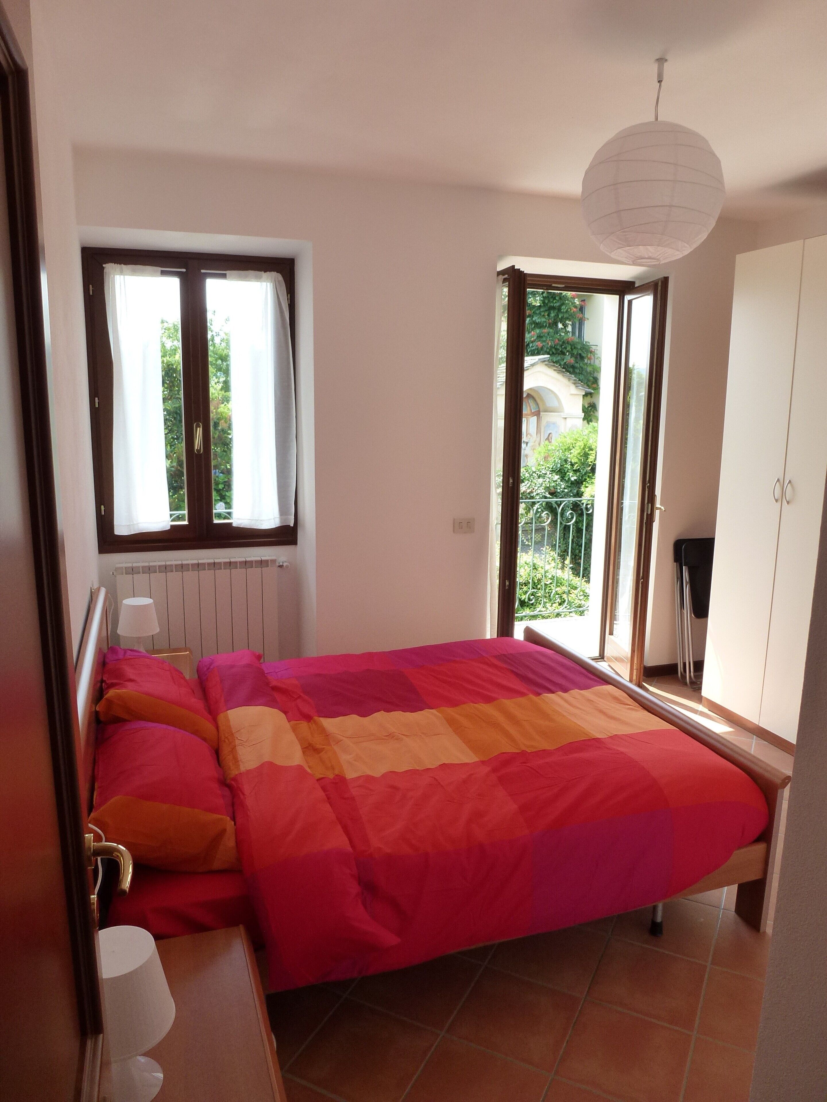 Une chambre à coucher avec un lit, une fenêtre, un radiateur et un balcon.