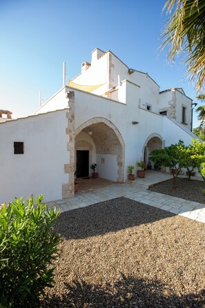 A building with a courtyard, stone arches, and potted plants. - Beautifully restored 16th Century farmhouse with large private pool  (Castellana Grotte)