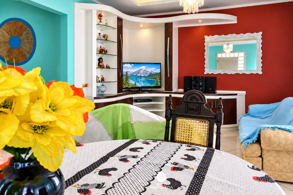 A living room with a television, a decorative mirror, and a dining area with a table set for two.