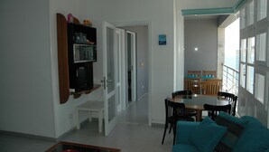Un salon comprenant un canapé, une table basse, un téléviseur et un coin repas avec une table et des chaises.