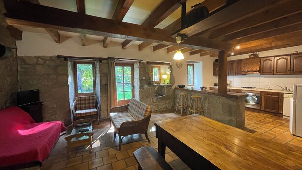 A cozy room with a wooden bench, a red sofa, and a stone wall.