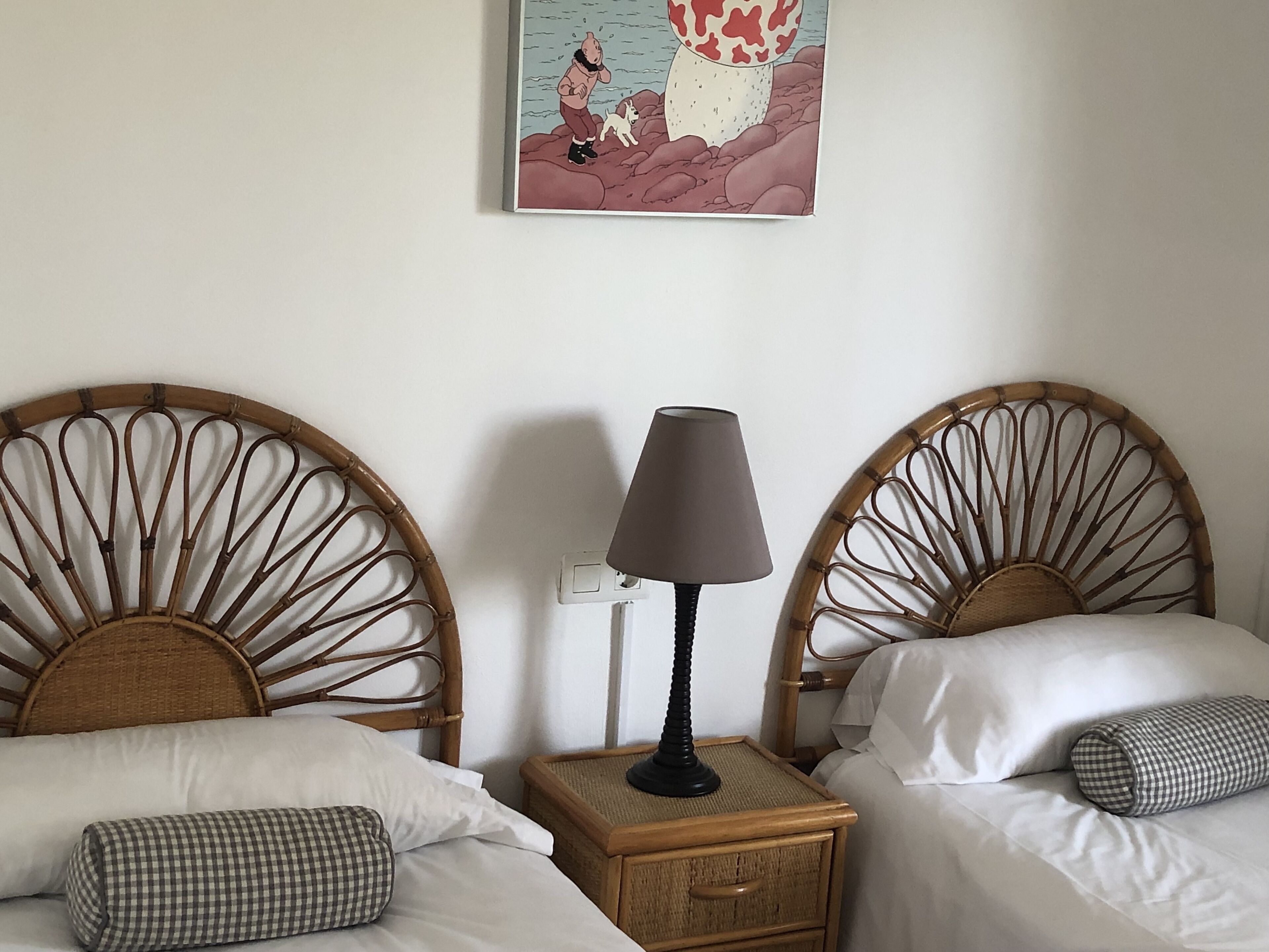 Ein Hotelzimmer mit zwei Einzelbetten, einem Nachttisch mit Lampe und einem Wandbild.