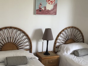 Ein Hotelzimmer mit zwei Einzelbetten, einem Nachttisch mit Lampe und einem Wandbild.