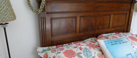 A wooden headboard with floral bedspread and a pillow with a beach scene.