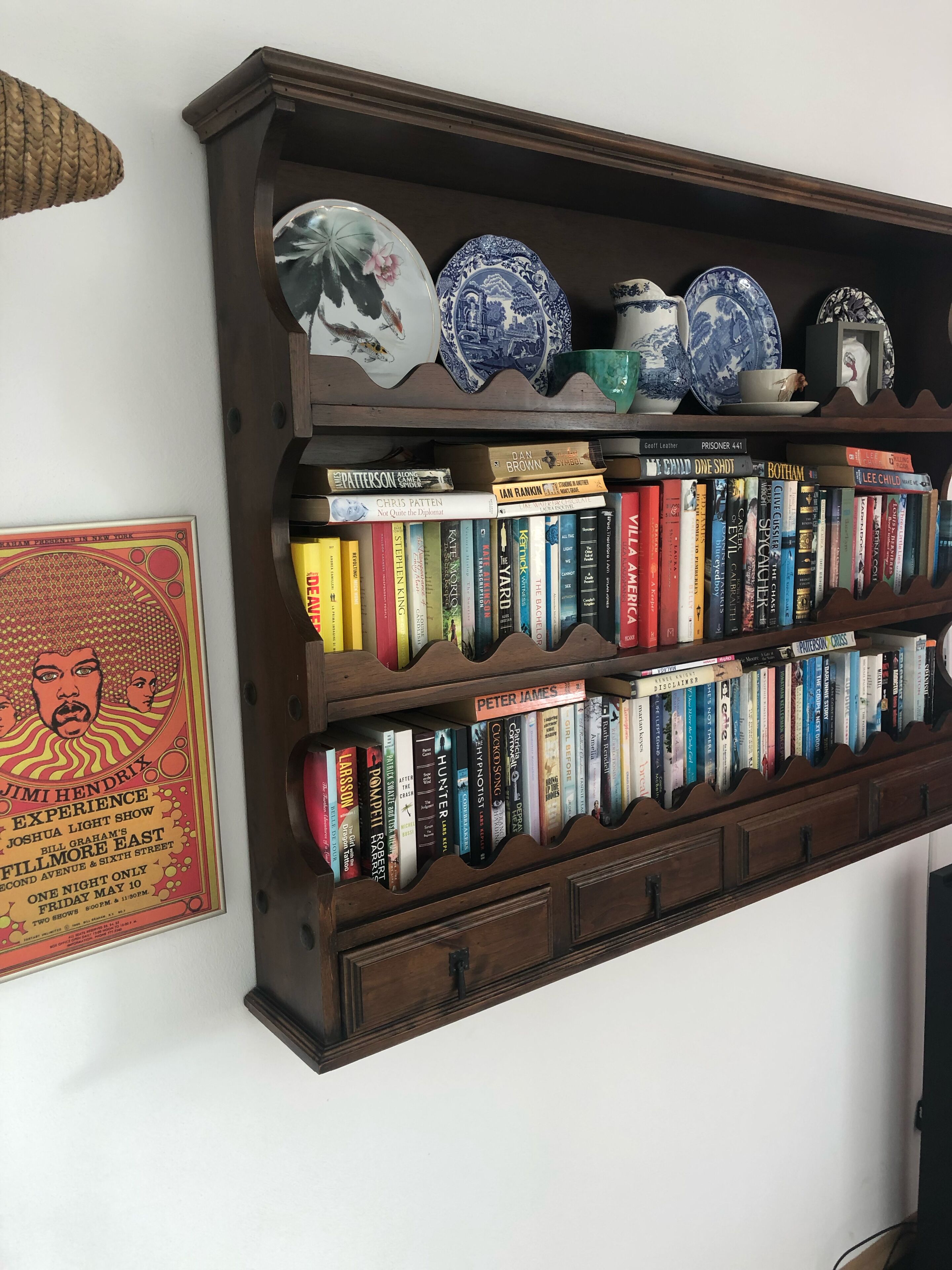 A bookshelf with various books and decorative plates.