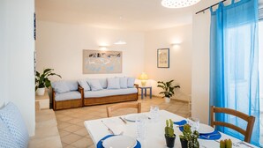 A dining area with a white table set for two, a blue sofa, and a lamp.