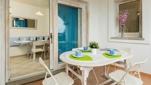 A dining area with a round table, chairs, and a view through a glass door.