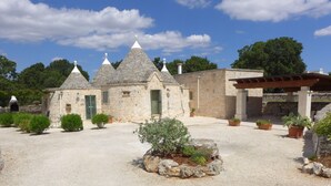 A stone building with multiple conical roofs, a gravel courtyard, and potted plants. - Beautifully Restored Trullo In Idyllic Location (Cisternino)
