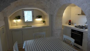 A compact kitchen with white cabinets, a checkered table, and a window above the sink. - Beautifully Restored Trullo In Idyllic Location (Cisternino)