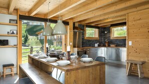 Una cocina moderna con una isla central, vigas de madera y grandes ventanales con vistas a un paisaje pintoresco.