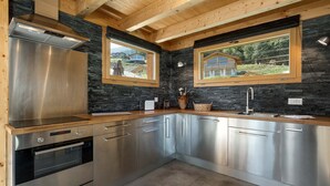 Una cocina moderna con electrodomésticos de acero inoxidable, vigas de madera y ventanas amplias con vistas a un paisaje pintoresco.