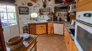 A kitchen with wooden cabinets, a sink, a dishwasher, and a stove. There is a window with a view of the outside.
