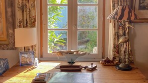 A wooden desk with a window, a lamp, and a framed picture.