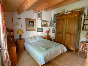 A bedroom with a bed, wooden wardrobe, and a bookshelf.