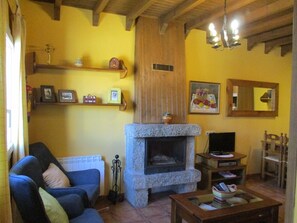Ein gemütliches Wohnzimmer mit Kamin aus Stein, einem blauen Sofa und einem Fernseher.