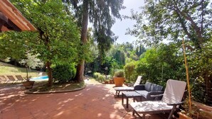 Un espace patio doté d’un sol carrelé, de mobilier d’extérieur et d’une végétation luxuriante.