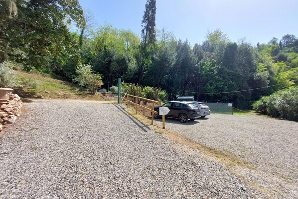 A gravel driveway leading to a gated parking area with a car parked inside. - Villa La Pieve, villa with pool and A/C, in Camaiore (Camaiore)