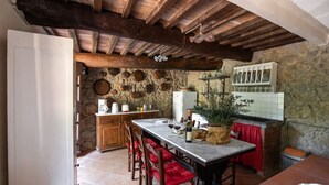 Une cuisine rustique avec un mur en pierre, des poutres en bois et un sol carrelé.