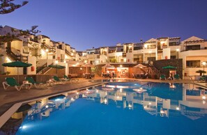 Un complejo turístico con piscina, mobiliario exterior y varias construcciones con balcones.