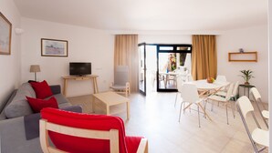 A modern living room with a sofa, TV, and dining area. - Club Oceano 2 bedroom Apts. (Puerto del Carmen)