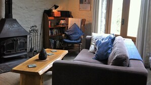 Uma sala de estar acolhedora com lareira, um sofá, uma mesa de madeira e uma estante de livros.