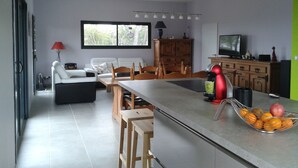 A modern kitchen with a dining area, a sofa, and a TV. - Newly built, secluded villa with a pool—sleeps 8 to 12—sauna—air conditioning (Saint-Julien-De-Peyrolas)